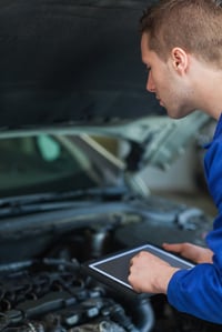 Male mechanic using digital tablet while examining car engine